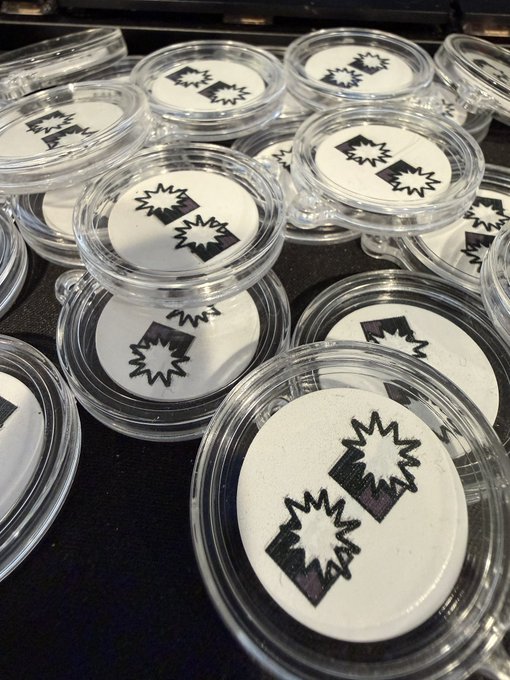 Several clear plastic coin capsules containing white coins stamped with a black 'POP!' comic-style explosion graphic.