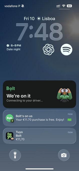 iPhone lock screen showing 7:48 AM on Friday in Lisbon with a Bolt ride notification "We're on it - Connecting to your driver..." and a free €11.70 purchase confirmation.