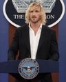 A blonde woman speaks at a podium bearing the 'The Pentagon' seal, with 'THE PENTAGON' text visible in the background.