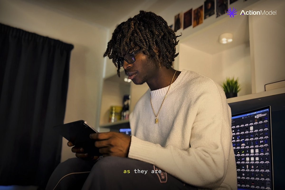 A young man with dreadlocks and glasses wearing a white sweater, sitting in a room looking at a tablet, with a computer monitor displaying a grid of images in the background; subtitle reads 'as they are' and logo shows 'ActionModel'.