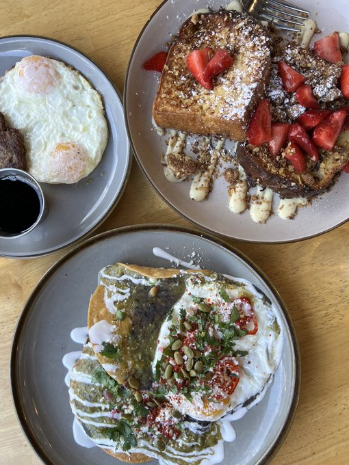 A delicious weekend brunch spread featuring two sunny-side-up eggs with sausage, stuffed French toast topped with strawberries, and huevos rancheros garnished with pumpkin seeds, cilantro, and crema — the perfect way to fuel a great weekend. ☀️🍳