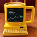 A novelty teapot device displays a stock chart for 'BTC-USD' on its screen above a built-in keyboard.