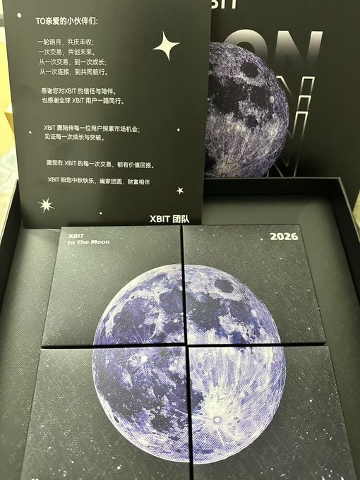 A XBIT Mid-Autumn Festival gift box featuring a black "To The Moon 2026" design with a split image of a detailed moon on four square coasters, accompanied by a card with the message "一轮明月，共庆丰收；一次交易，共创未来" addressed to "XBIT 团队."