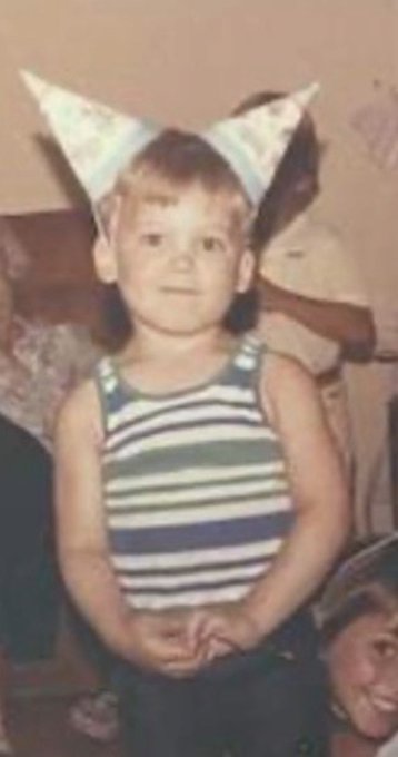 A vintage photo of a young child wearing a striped tank top and a handmade cat-ear headband.