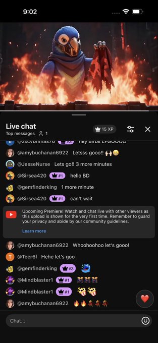 YouTube mobile app screenshot showing a Premiere Watch live stream for what appears to be Hellfire Gala content featuring a fiery character, with a live chat full of viewer comments and reactions.