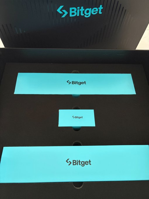 An open black promotional box displays three bright teal panels with the white 'Bitget' logo, matching the logo shown on the inside lid of the box.