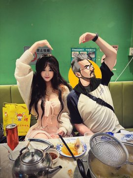 A couple poses together at a dining table with food and a teapot, forming a heart shape with their arms raised. Behind them are green walls with signs displaying "禁止吸烟" (No Smoking) and other Chinese text, aligning with the post celebrating a meal of crispy grass carp.