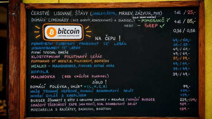 A Czech-language restaurant chalkboard menu accepting Bitcoin (Lightning), listing fresh juices, lemonades, non-alcoholic cocktails, and food items with prices in CZK.