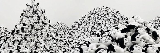 A surreal black-and-white image featuring massive piles of small doll-like figures with oversized heads, stacked into mountain-like heaps.