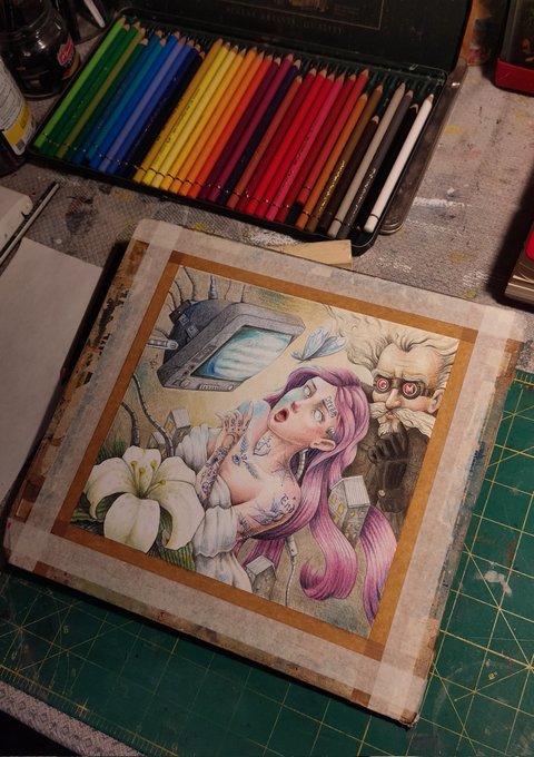 A pencil illustration taped to a wooden board sits beneath an open tin of colored pencils, depicting a pink-haired woman with a cybernetic eye and tattoos alongside a bearded figure wearing goggles and a small robot, matching the post's description of "EX-TASY," the first piece in the MTK-Protocols collection, rendered in pencils on 20.20 cm cardboard.