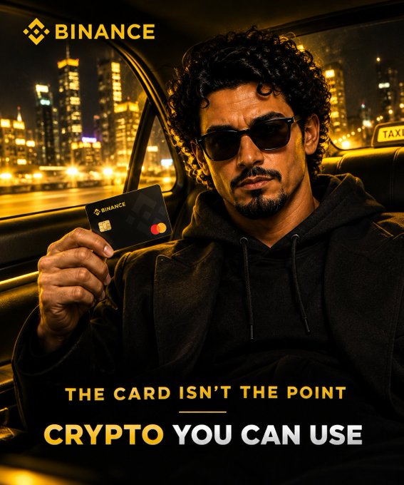 A man wearing sunglasses sits in a taxi at night, holding up a black Binance-branded Mastercard against a glowing city skyline. The ad's text reads "THE CARD ISN'T THE POINT — CRYPTO YOU CAN USE," reinforcing the post's message that the Binance Card allows eligible users to spend their crypto directly on everyday purchases without first converting it.