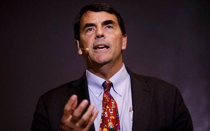 A man wearing a dark suit, light blue shirt, and a colorful tie gestures while speaking into a headset microphone during what appears to be a presentation, illustrating the post's reference to venture capitalist Tim Draper and his bold $250,000 Bitcoin price prediction.