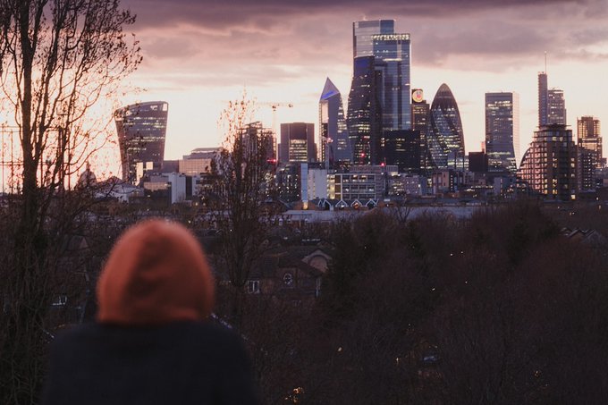 A person with red hair silhouetted against the London skyline at dusk, with recognizable buildings including the 'Walkie Talkie' visible.