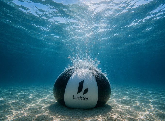 Underwater scene showing a black and white ball labeled 'Lighter' splashing into the sandy ocean floor with bubbles rising through blue water toward the surface.