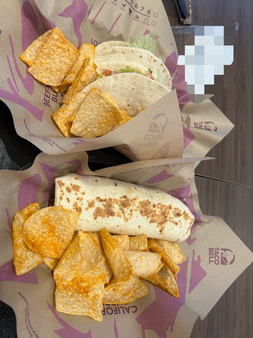 A Taco Bell meal featuring a soft tortilla wrap and seasoned nacho chips served on branded Taco Bell wrappers, perfect for celebrating Taco Tuesday with "Good Morning" vibes.