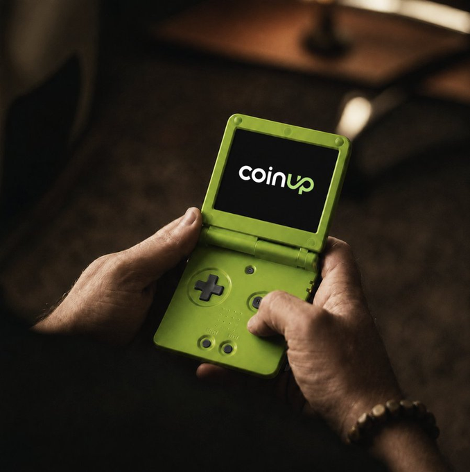 urn of gold sits on a wooden table, with a person holding a green Nintendo DS game controller and the word "coinup" displayed on its screen.