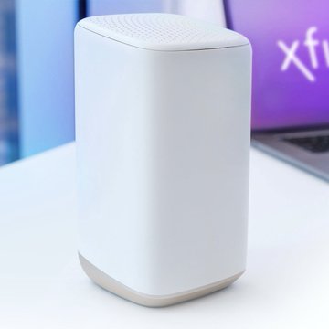 A sleek white wireless router sits on a desk with a laptop displaying "xfi" in the background, suggesting it was likely purchased based on the poster's earlier claim about needing a better internet setup. The caption humorously implies the poster was correct in their prediction about needing to upgrade their networking equipment.