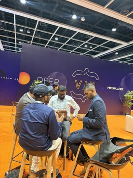 The team prepares for the India panel at DEFCON, seated together with laptops and phones in front of a backdrop reading "DEFCON VILLAGE" and "bitcoin," surrounded by event signage.