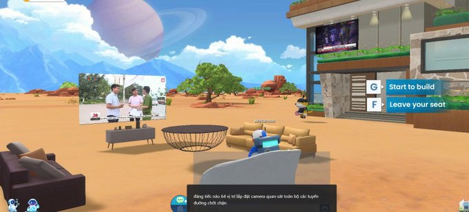 A virtual reality environment with a desert landscape showing avatars, furniture, a screen displaying a cooking video, and UI prompts to "Start to build" and "Leave your seat," with Vietnamese chat text at the bottom.