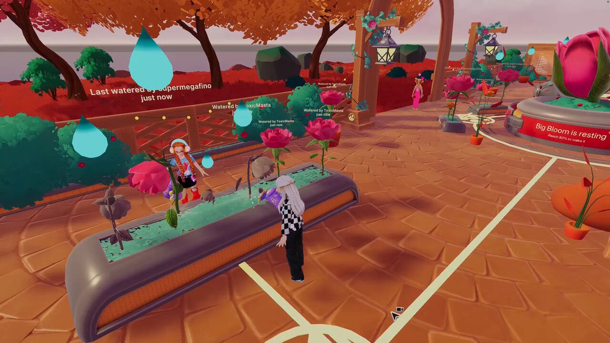 The image features a woman standing next to a large planter filled with flowers, surrounded by potted plants of various sizes. The scene takes place outdoors, possibly at a park or garden area. A sign can be seen nearby that reads "No time to stop and smell the roses here! Grab your watering can and get to work Bring your garden back to life in Bloom Garden". This suggests that there is an ongoing gardening activity taking place within the game's environment, with players encouraged to engage in it by providing water for the plants.