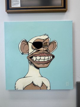 A framed canvas artwork displays a cartoon monkey with a large, toothy grin wearing a black eyepatch on a light blue background.