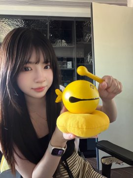 The image features a woman holding up a yellow ball with a stick, possibly a drumstick or maraca, as part of an online post. The caption reads "拆盲盒就是我们大儿童的情绪价值来源", which suggests that the woman is promoting a product related to music or drumming.