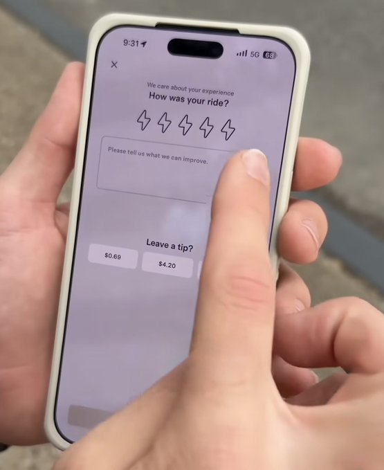 A person holds an iPhone displaying a ride rating screen asking 'How was your ride?' with lightning bolt rating icons, a feedback text box, and tip options of $0.69 and $4.20.