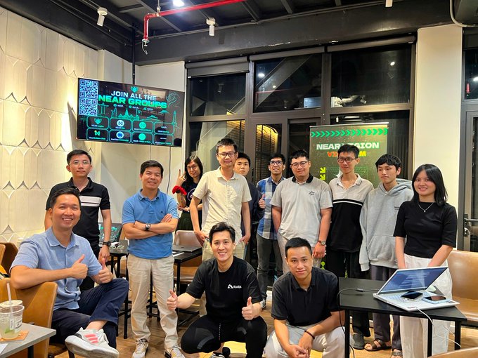 A group photo of approximately 12 people posing together indoors, with a TV screen displaying 'JOIN NEAR AI THE NEAR HORIZON' alongside a QR code. A second display behind them reads 'NEAR HORIZON VIETNAM', suggesting this is a gathering related to the NEAR AI Horizen event in Vietnam.