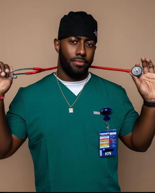 A professional photoshoot portrait of a Black male nurse wearing green scrubs, a black beanie, and holding a stethoscope in his mouth, with an 'RN' badge visible on his uniform.