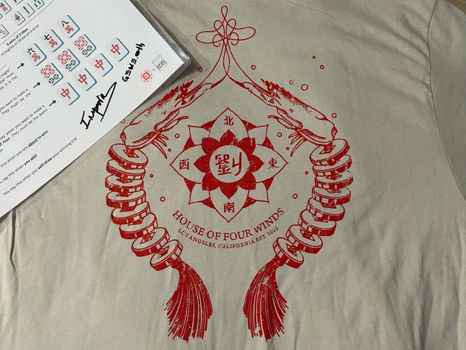 A cream tote bag displays a red "HOUSE OF FOUR WINDS - LOS ANGELES, CALIFORNIA EST. 3/3" mahjong tile crest featuring the 墨 (ink) tile flanked by East, South, West, and North directional characters, with a mahjong tile stack and tassel design; it sits next to what appears to be a Chinese language learning workbook titled "Hanyu." The image visually represents the post's theme of "mahjong maxis" emerging from the BAYC sub-community culture.