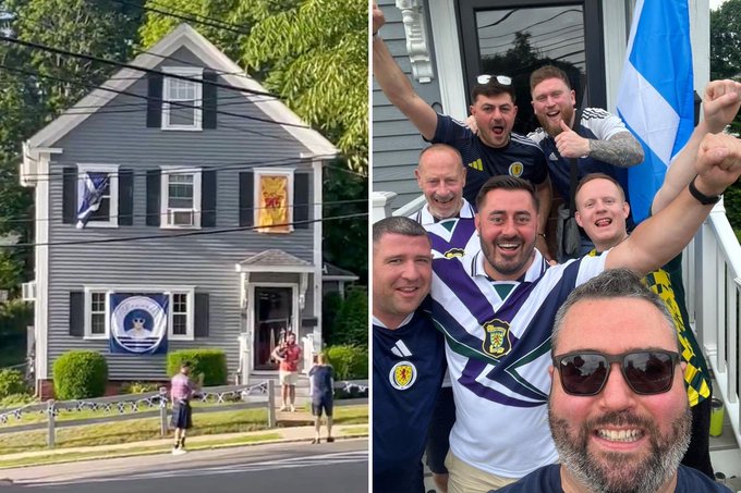 A group of jubilant Scottish soccer fans pose together in front of a New England home decorated with a Scotland flag and banner, celebrating alongside the "MDMorrison82" who shared the moment, evoking the cross-cultural camaraderie of an Airbnb meet-up between Scottish World Cup supporters and a Boston local on NFL Sunday.