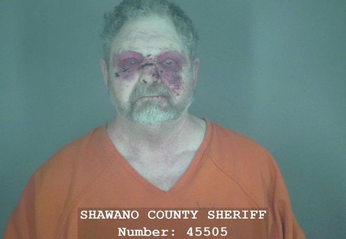 urn of blood stains on a man's face, wearing an orange shirt and white collar, with the name "Shawano County Sheriff" and number 45505 displayed.