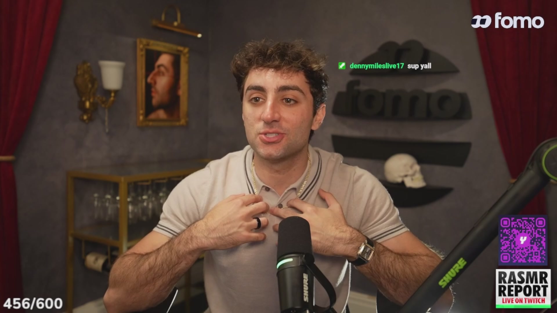 urns of gold and silver, framed painting, black microphone, green and white logo, purple and white text box, and a man's face on the screen.