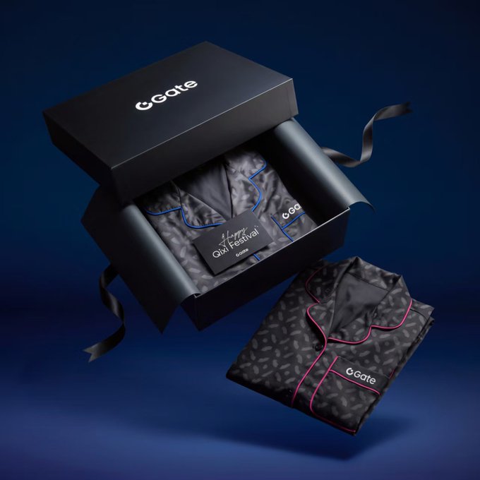 A luxury black gift box from 'CGate' containing patterned silk pajamas with pink piping, labeled 'Happy QIXi Festival', set against a dark blue background.