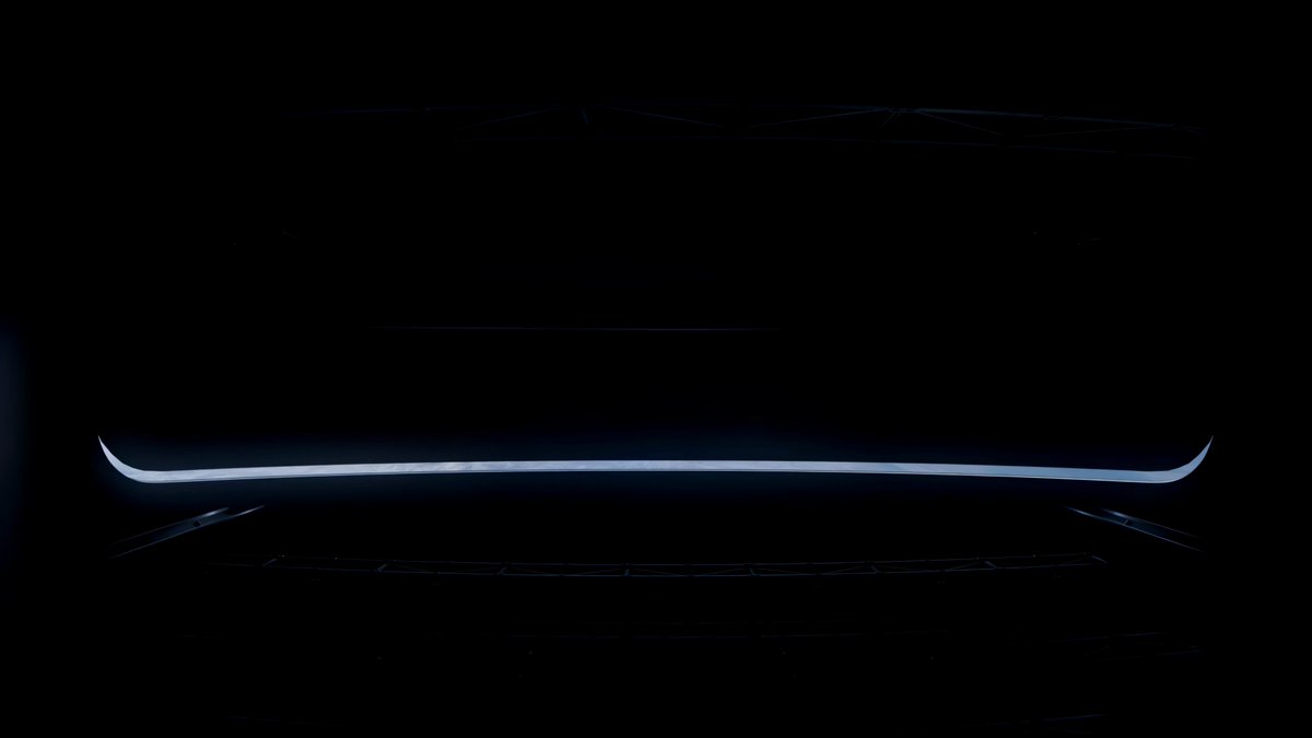 The image shows a car's rear view mirror, which appears to be black with white lines or stripes running through it. The background of the photo is dark, making the mirror stand out prominently against the darkness. There are no other objects or people visible in the image, and the focus is solely on the rear view mirror.
