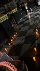 Looking down from a dizzying height, the image shows a black-and-white checkered floor far below, illuminated by scattered floor lights along a dark interior space—suggesting the disorienting perspective of someone who couldn't see where they were stepping. The caption reflects how, while blindfolded, they could only later behold this vertiginous view of the architectural space below.