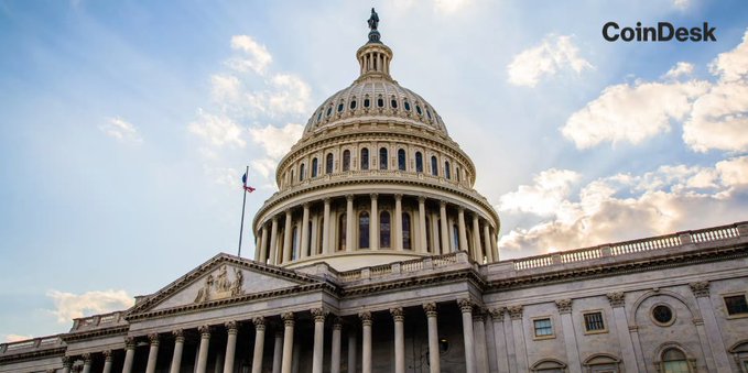 The U.S. Capitol building stands under a partly cloudy sky, with the "CoinDesk" watermark visible in the upper right corner. The image's connection to the accompanying post is that it depicts the very seat of legislative power where the bipartisan ethics compromise on the CLARITY Act—which would grant state attorneys general crypto enforcement authority alongside the DOJ—is being negotiated and potentially voted on before the August recess.