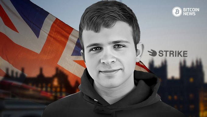 A stylized black-and-white illustration of a young man wearing a hoodie, set against a backdrop featuring the British Union Jack flag, the Houses of Parliament silhouette, and the "STRIKE" company logo, tying into the post's announcement of Strike launching its new Stacks bitcoin savings envelope system in the UK.