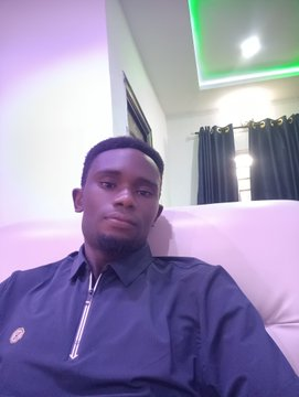A young man wearing a dark shirt poses for a close-up selfie in a room with pink and green LED lighting. The image serves as a personal introduction accompanying his profile description as a Crypto Researcher, Airdrop Hunter, and DeFi Explorer.