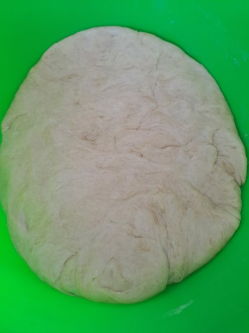 A round ball of smooth, raw dough rests on a bright green surface.