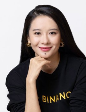 The image features a woman with long black hair wearing a black sweater, posing for a photo against a white background. The woman has her hand placed on her chin, giving off a confident and relaxed demeanor. In the background of the image, there is text that reads "NEW: Binance co-founder Yi He became the first crypto-native executive to be named to Fortune's Most Powerful Women global list." This suggests that the woman in the photo might have made significant contributions to the world of cryptocurrency or has been recognized for her achievements.