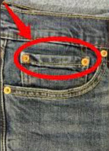 A close-up of blue jeans with a red arrow and circle pointing to the small pocket detail above the main front pocket.