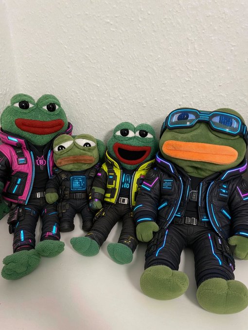 Four Pepe the Frog plush toys dressed in detailed cyberpunk-style outfits with glowing neon accents and goggles, arranged in a row.