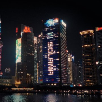 Illuminated Shanghai skyscrapers at night display "cit" (Citi) and "Hill" signage, setting the urban backdrop for news that Solana postponed its Shanghai event due to overwhelming registration demand.