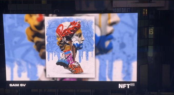 A digital billboard at night displaying a colorful graffiti-style NFT artwork with the text 'SAM SV' and 'NFT NYC'.