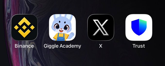 A phone home screen displays four app icons in a row: Binance, Giggle Academy, X, and Trust (wallet), humorously imagining the apps that crypto influencer CZ's phone would prominently feature.