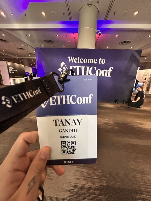 The image shows a person holding up an identification card with their name on it, which appears to be a lanyard or badge. The background of the photo features a large blue sign that says "Welcome to EthCon". This suggests that the person is attending an event related to ethical hacking and computer security.