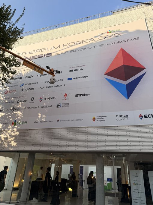 A large banner on a building exterior for 'Ethereum Korea Genesis,' displaying logos of sponsors like Optimism, Polygon, DSRV, and others, with the subtitle 'Build Beyond the Narrative.'