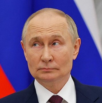 A man in a dark suit and tie stands before a Russian flag, his serious expression reflecting the gravity of the news that Russia's Moscow Exchange will begin trading Bitcoin, Ethereum, and USDT starting December 1st.