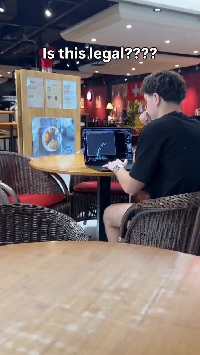 A young man sits at a cafe table using a laptop displaying a financial chart, with text overlay reading 'Is this legal????' and a Swiss flag visible in the background.